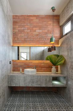 an instagram photo of a bathroom with brick walls and concrete countertops, along with a plant in the corner