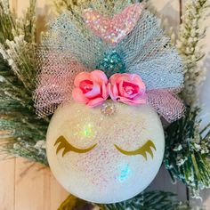 a white ornament decorated with pink roses and glitters on top of a tree