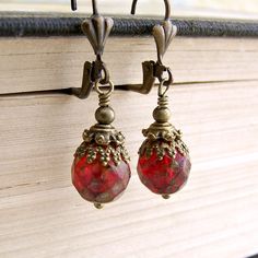 Get ready for a carnival in Venice with these red and brass earrings. The ornate brass caps mimic the charm and grandeur of Venice. The red faceted Czech glass beads have a Picasso finish that make the beads appear to have an aged patina. Depending on the light they can either glow a warm red or have a deeper matte red look.   From the top curve of the lever back ear wires to the bottom of the ball tipped head pin these earrings measure 1 1/2 inches (3.7 cm) long. Other ear wire styles are avail Cheap Red Czech Glass Earrings, Ornate Red Dangle Earrings, Ornate Red Earrings For Party, Red Faceted Beads Earrings For Festive Occasions, Ornate Red Teardrop Jewelry, Elegant Red Czech Glass Earrings, Vintage Red Brass Earrings, Vintage Red Teardrop Jewelry, Vintage Czech Glass Beaded Earrings As Gift