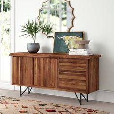 a wooden sideboard sitting on top of a rug next to a potted plant