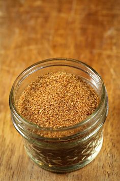 a glass jar filled with spices on top of a wooden table