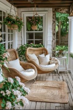 two wicker chairs sitting on top of a wooden porch next to flowers and potted plants