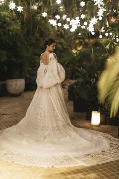 a woman in a white wedding dress standing on a brick floor next to potted plants