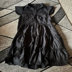 Never Worn Black Dress With Ruffles Going Along The Dress And Buttons! Very Flowy Casual Black Summer Tiered Dress, Chic Black Tiered Dress With Ruffles, Casual Black Tiered Summer Dress, Casual Black Ruffle Dress, Casual Black Ruffle Hem Dress, Black Mini Dress With Ruffle Hem And Sleeves, Black Casual Tiered Dress With Ruffles, Black Ruffle Sleeve Dress For Summer, Black Tiered Dress With Ruffle Hem For Spring