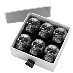 six silver skulls in a white box