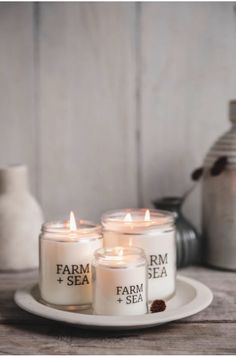 three candles sitting on top of a white plate next to some jars and vases