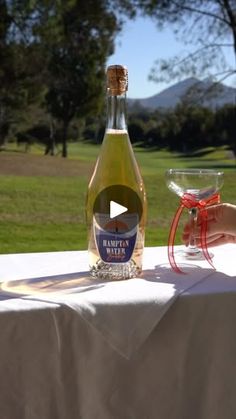 a bottle of wine sitting on top of a table next to a glass filled with liquid