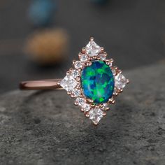 an opal and diamond ring sitting on top of a rock