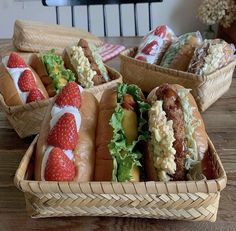 four baskets filled with hot dogs and strawberries on top of a wooden table in front of a television