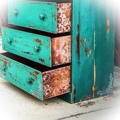 an old dresser is painted turquoise and has rusted drawers