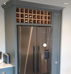 a stainless steel refrigerator in a kitchen with wine bottles on the door and shelves above it