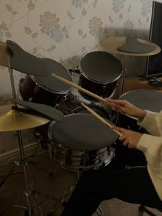 a person sitting in front of a drum set with two sticks sticking out of it