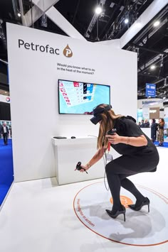 a woman in black dress and heels playing with a remote control at a trade show