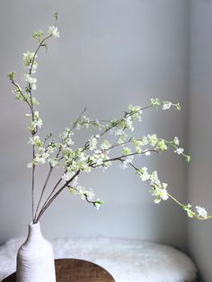 a white vase filled with flowers on top of a wooden table