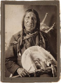 an old black and white photo of a native american man holding a plate in his hands