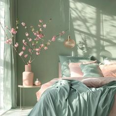 a bed room with a neatly made bed and pink flowers in vases on the side