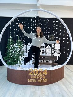 a woman standing on top of a snow globe in front of a christmas tree and building