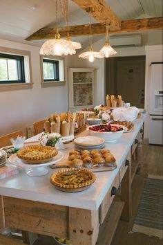 a table filled with lots of food on top of a white counter topped with pies