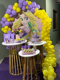 the table is set up with balloons and decorations for a princess themed birthday party in purple, yellow and white