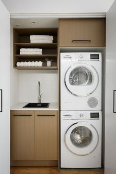 a washer and dryer in a small room with wooden cabinets on the wall