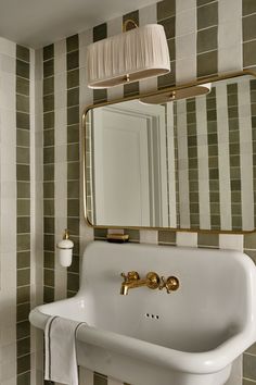 a white sink sitting under a bathroom mirror next to a wall mounted faucet