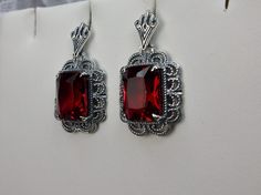 Simulated Red Ruby Solid Sterling Silver Earrings Short Festoon Design#E8z (shorter version) These Victorian reproduction estate earrings are solid sterling silver. These filigree earrings have stunning simulated red ruby gemstones. Each stunning gem is 10mm x 8mm x 5mm in dimension. The earrings are approximately 1/2" x 1" (13mm x 23mm). The unique earrings are marked 925 for solid sterling silver. These lovely earrings were refashioned from an antique Victorian cameo necklace. Quintessentially Red Jewelry Set, Jeweled Flowers, Armenian Jewelry, Red Stone Ring, Marcasite Jewelry, Filigree Jewelry, Mid Century Jewelry, Red Jewelry, Filigree Earrings