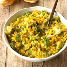 a white bowl filled with corn and broccoli on top of a wooden table