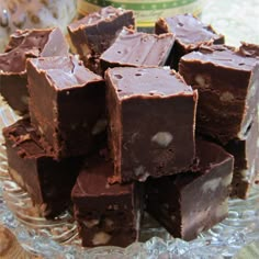 a pile of chocolate fudges sitting on top of a glass plate covered in frosting