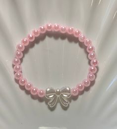 Pearl bow bracelet. Super cute for a pink look. Round Bead Bracelets, Cute Things To Make With Beads, Pink Ribbon Jewelry As Gift, Pink Ribbon Jewelry Gift, Pink Ribbon Jewelry For Gifts, Cute Adjustable Bow As Gift, Feminine Pink Bracelets For Gift, Cute Bow With Butterfly Knot For Gifts, Elegant Adjustable Jewelry With Pink Bow