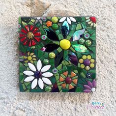 a mosaic tile with flowers and leaves on the side of a stone wall or floor