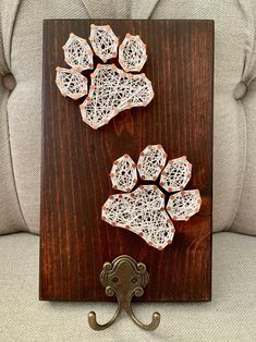 two pieces of string art sitting on top of a wooden board