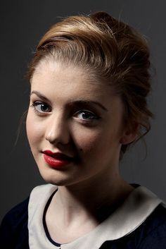 a woman with red lipstick and black makeup looks at the camera while posing for a photo