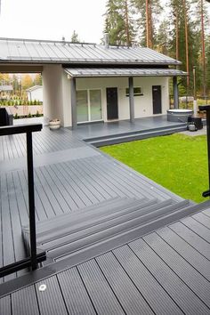 a house with a metal roof and wooden decking on the front yard, looking out onto the back yard