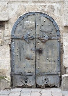 an old metal door is open on the side of a stone building with cobblestone flooring