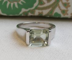 ✦✦ 8x10mm emerald cut  Green Amethyst is prong set in Sterling silver. ✦✦ Band width is approximately 3.37mm at the widest point by the stone and 1.54mm at thinnest point in the back.  This will be sent from Oslo  Introducing our exquisite 8x10mm green amethyst sterling silver ring, featuring a stunning emerald cut prasiolite stone. This ring is the perfect addition to any jewelry collection, offering a unique and timeless look that is sure to turn heads. Crafted from high-quality sterling silver, this ring boasts a lustrous and durable finish that will stand the test of time. The 8x10mm green amethyst stone is the centerpiece of this piece, showcasing a vivid and vibrant green hue that is truly captivating. The emerald cut of the prasiolite stone allows for maximum light reflection, creat Classic Green Amethyst Ring As Gift, Classic Green Amethyst Ring Gift, Classic Green Amethyst Ring For Gift, Silver Emerald Ring With Rectangular Stone For Gift, Silver Emerald-cut Emerald Ring As Gift, Sterling Silver Emerald Ring With Square Cut As Gift, Square Cut Emerald Ring In Sterling Silver, Classic Amethyst Ring With Rectangular Stone For Gift, Green Amethyst Sterling Silver Ring Gift