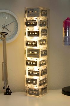 a stack of cassettes sitting on top of a white table next to a clock