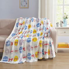 a white couch sitting next to a window covered in a colorfully colored blanket on top of a hard wood floor