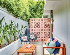 an outdoor seating area with wooden furniture and plants on the side of the house,