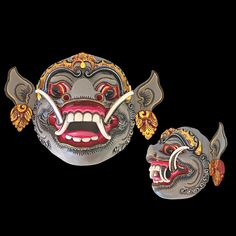 two metal masks with red and yellow designs on them, one has an open mouth