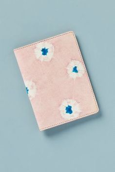 a pink notebook with white and blue flowers on the cover, sitting on a blue surface