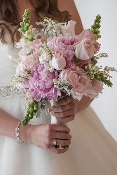 a bride holding a bouquet of pink and white flowers