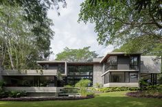 a modern house in the middle of a lush green park with lots of trees and bushes