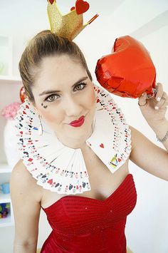 a woman in a red dress holding up a heart shaped card and wearing a crown on top of her head