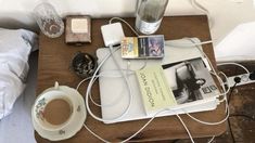 a wooden table topped with a cup of coffee next to a book and other items