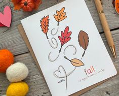 an autumn card with leaves and acorns next to yarn balls, crocheted pumpkins and felt hearts