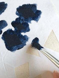 someone is painting something with blue paint on white paper