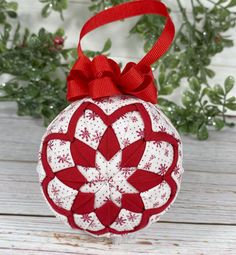 a red and white ornament with a bow on the top sitting on a table