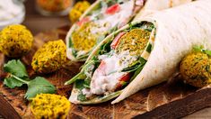 several burritos on a cutting board with herbs