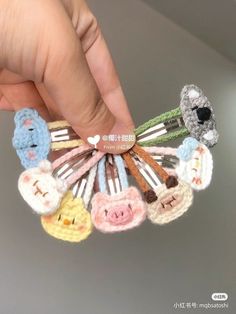 a person holding several small crocheted animal clips in their hand, each with different colors