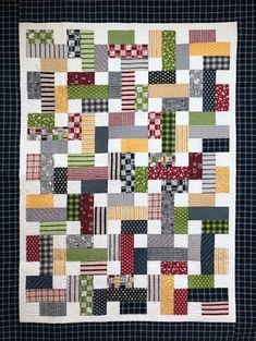 a patchwork quilt with squares and stripes on the front, in green, yellow, red